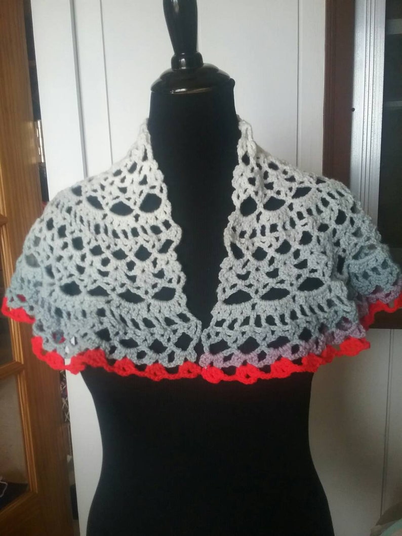 Shawl trimmed in red two fasteners pins one red one blue crocheted by hand.