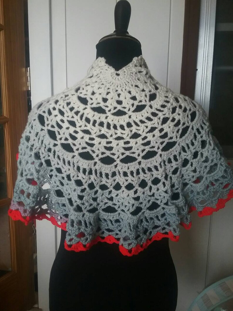 Shawl trimmed in red two fasteners pins one red one blue crocheted by hand.