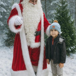 May include: A person dressed as Santa Claus in a red suit with white fur trim and a child in a blue hat and black jacket standing in a snowy forest. The child is wearing gray pants and brown boots.