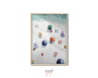 May include: A framed print of a beach scene with colorful umbrellas, beach towels, and the ocean. The artwork features a top-down perspective, with a light-colored sandy beach and turquoise water. The umbrellas are various colors, including green, orange, and blue.