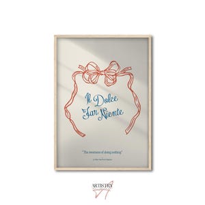 May include: Framed art print with a light beige background. The artwork features a red bow and ribbon design with the words "Il Dolce Far Niente" in blue script. Below, it reads "The sweetness of doing nothing."