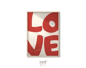 May include: A framed art print featuring the word "LOVE" in large, bold, red letters against a cream-colored background. The print has a minimalist design with a wooden frame. The phrase "is the key" is written in cursive at the bottom.