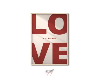 May include: A framed print with the word "LOVE" in large red letters, with the text "IS ALL YOU NEED." in smaller letters below. The background is a light beige color.