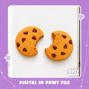 May include: A digital 3D print file featuring two golden-brown chocolate chip cookies on a white surface. One cookie is whole, and the other has a bite taken out of it. The text Cozy Designs and Digital 3D Print File are visible on the image.