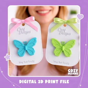 May include: Two white rectangular display cards featuring the text Cozy Designs and Tiny but lovely. One card holds a bright blue butterfly, the other a lime green butterfly. Each card is topped with a satin ribbon bow in pink or light green.