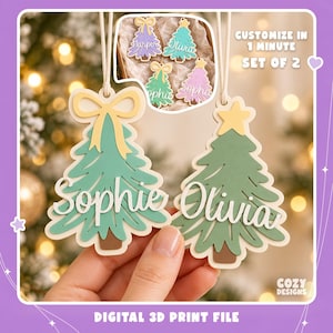 May include: Two layered Christmas tree ornaments with white string hangers. One tree features a yellow bow and the name Sophie, the other a yellow star and the name Olivia. Text reads: Customize in 1 minute, set of 2, and digital 3D print file.