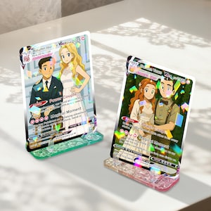 May include: Two Pokemon card displays showing couples in wedding outfits. The cards have holographic details and are set in clear acrylic stands with coloured bases. Text includes "Power Couple" and "Magical Moment."