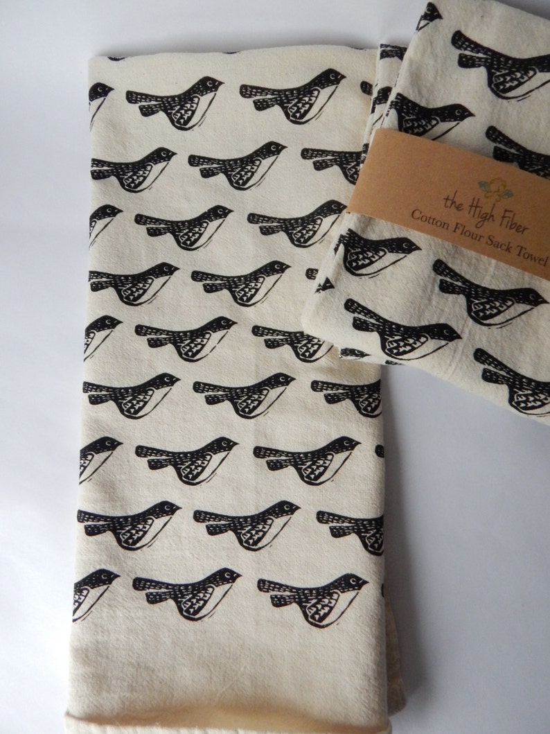 May include: Two white cotton flour sack towels with a black bird pattern and the text "the High Fiber Cotton Flour Sack Towel".
