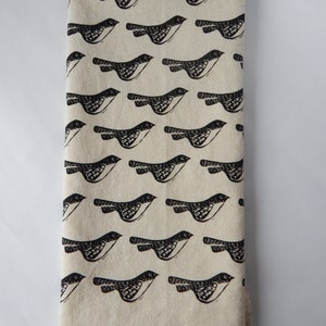 May include: A white kitchen towel with a black and white repeating pattern of birds. The birds are stylized and have a simple design.