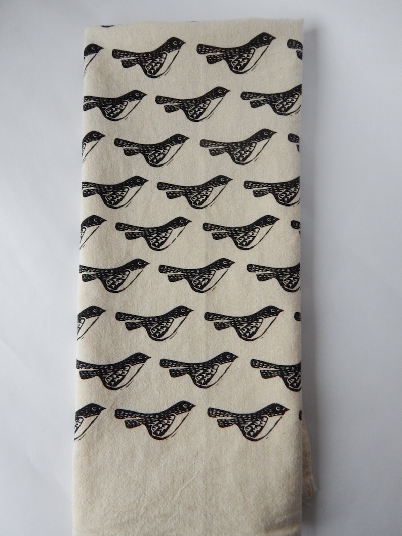 May include: A white kitchen towel with a black and white repeating pattern of birds. The birds are stylized and have a simple design.
