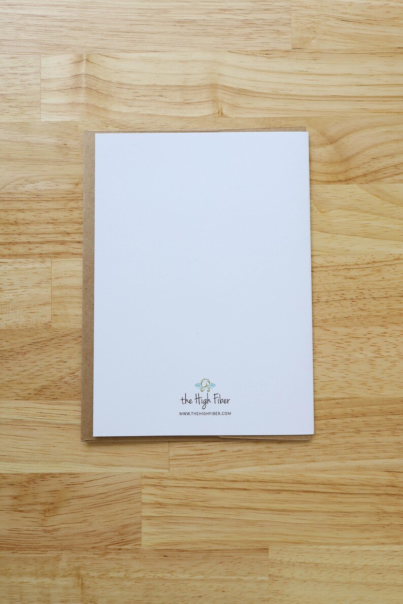 May include: A white card with a brown border, on a wooden surface. The card has the text "the High Fiber" and the website address www.thehighfiber.com.
