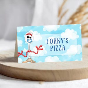 Op de afbeelding: Een gevouwen kaart met Forky uit Toy Story tegen een blauwe lucht met witte wolken. De kaart leest "Forky's Pizza" in blauwe tekst. Forky wordt afgebeeld als een witte spork met rode armen en een lachend gezicht.