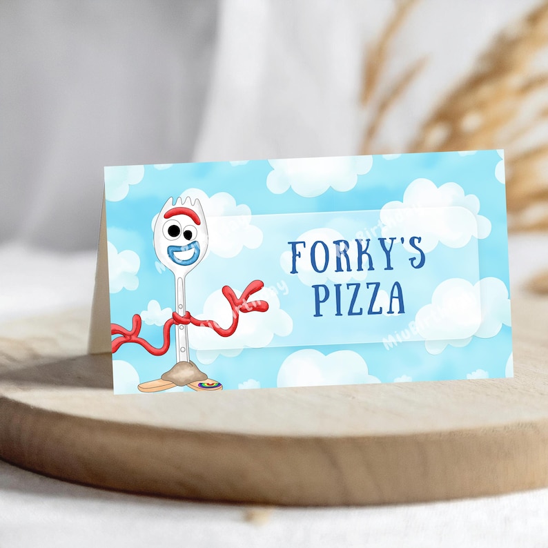 Op de afbeelding: Een gevouwen kaart met Forky uit Toy Story tegen een blauwe lucht met witte wolken. De kaart leest "Forky's Pizza" in blauwe tekst. Forky wordt afgebeeld als een witte spork met rode armen en een lachend gezicht.