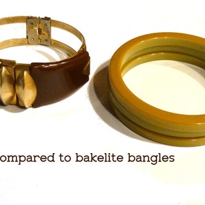 May include: Two bracelets, one brown with gold accents and a hinged clasp, and one yellow bakelite bangle.