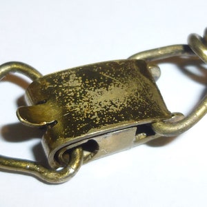 May include: A brass clasp with a spring-loaded mechanism. The clasp is worn and has a patina finish.