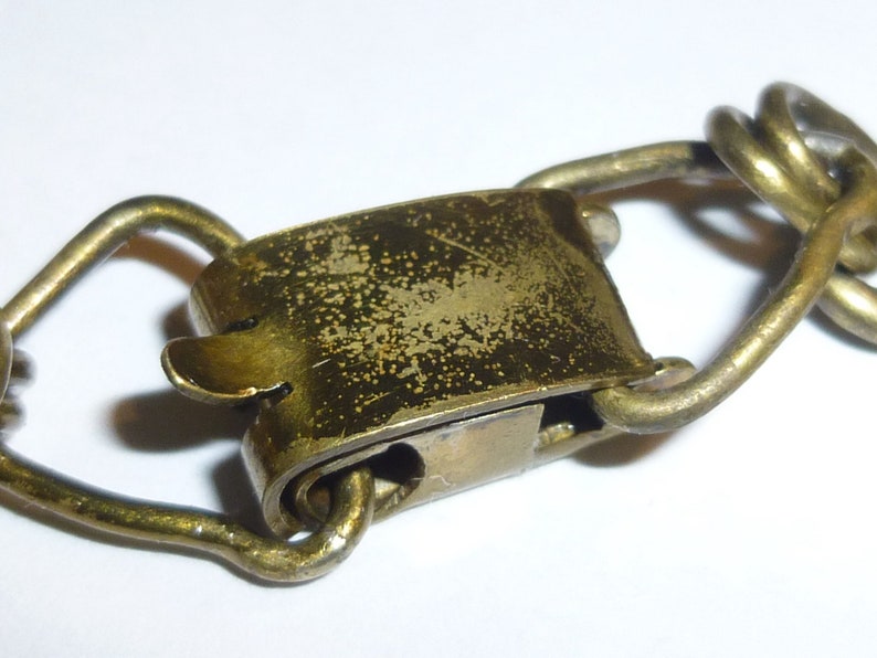 May include: A brass clasp with a spring-loaded mechanism. The clasp is worn and has a patina finish.