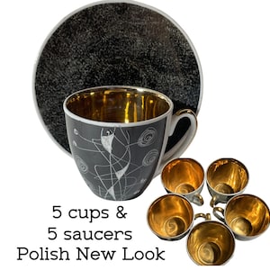 May include: A set of 5 cups and 5 saucers featuring a dark gray exterior with white line drawings and a metallic gold interior. The saucers have a textured black finish. The text 5 cups & 5 saucers Polish New Look is printed below the items.