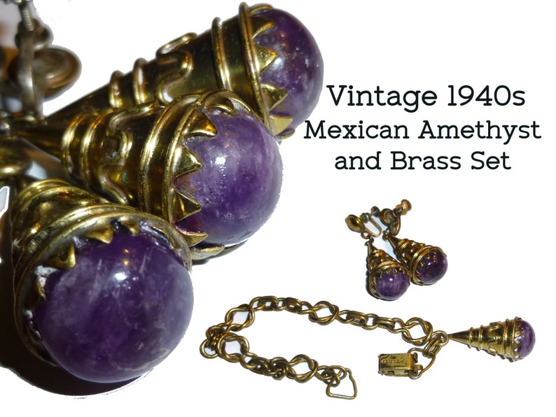May include: A vintage 1940s set of amethyst and brass jewellery. The set includes a necklace, a pair of earrings, and a bracelet. The amethyst stones are a deep purple colour and are set in ornate brass settings. The necklace features a pendant with a large amethyst stone and a chain with a clasp. The earrings are drop earrings with amethyst stones and brass settings. The bracelet is a chain bracelet with a clasp.