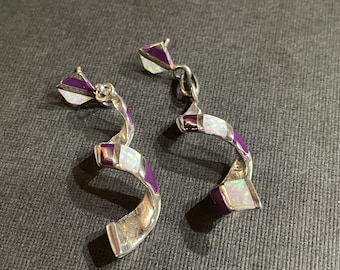 May include: A pair of silver earrings with a spiral design. The earrings are decorated with purple and white opal stones.