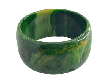 May include: A green and yellow marbled plastic bangle bracelet. The bracelet is thick and has a smooth, glossy finish.