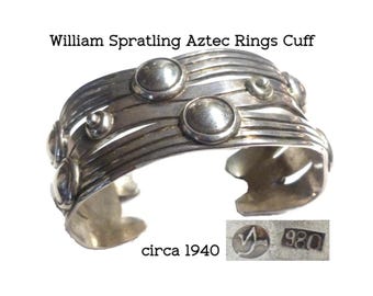 May include: Silver cuff bracelet with a textured design featuring multiple circular elements. The bracelet is marked "920" and "circa 1940".