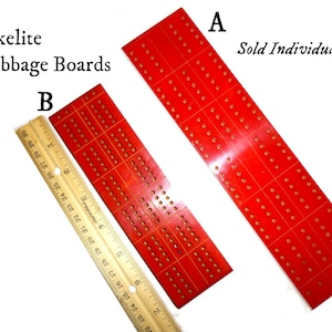 May include: Two red Bakelite cribbage boards, labeled A and B. The boards are made of a red plastic material with white dots and lines. The boards are sold individually. The text "Sold Individually" is printed on the image.