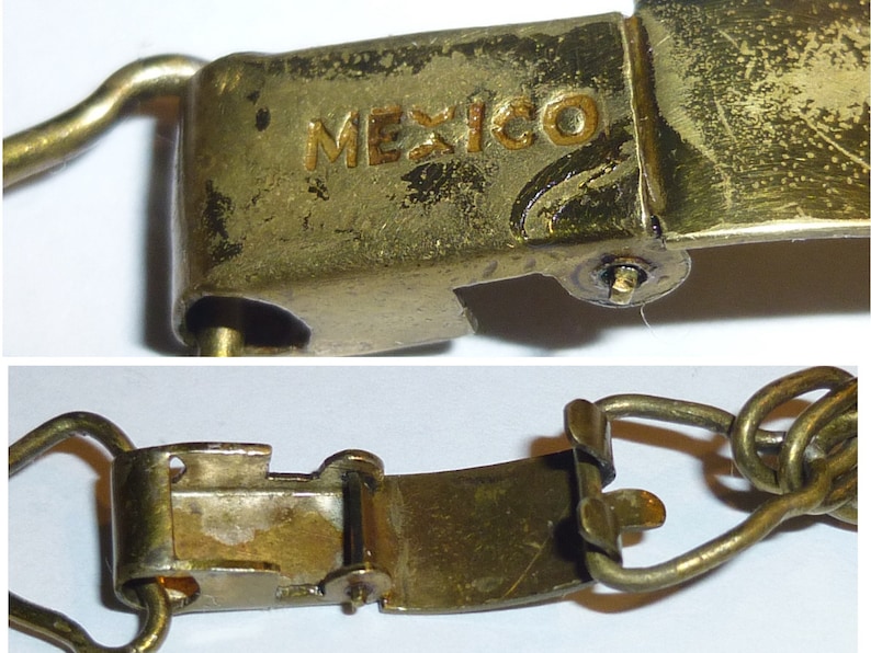 May include: A gold-coloured metal clasp with a hinged opening. The clasp has the word "MEXICO" engraved on it.