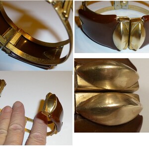 May include: A brown bakelite hinged bangle bracelet with gold-tone metal accents. The bracelet has two large, oval-shaped, gold-tone metal accents on the front.