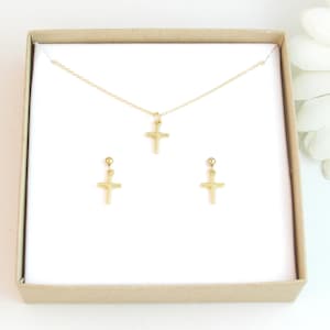 Peut inclure: Un ensemble de collier et boucles d'oreilles en forme de croix dorées dans une boîte cadeau blanche. Le pendentif et les boucles d'oreilles en forme de croix sont simples et délicats.