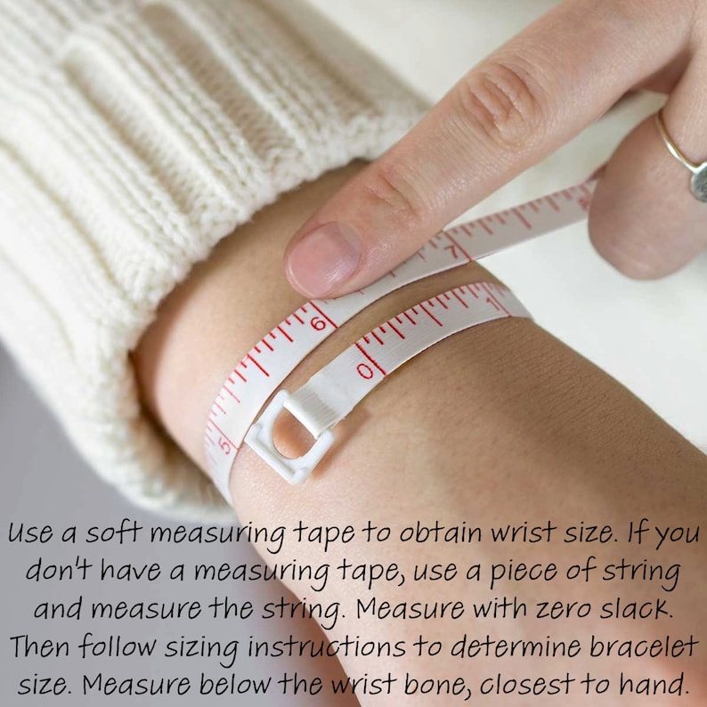 May include: A close-up of a person's wrist being measured with a white measuring tape. The tape is wrapped around the wrist and the person is holding the end of the tape with their finger. The text on the image reads: "Use a soft measuring tape to obtain wrist size. If you don't have a measuring tape, use a piece of string and measure the string. Measure with zero slack. Then follow sizing instructions to determine bracelet size. Measure below the wrist bone, closest to hand."