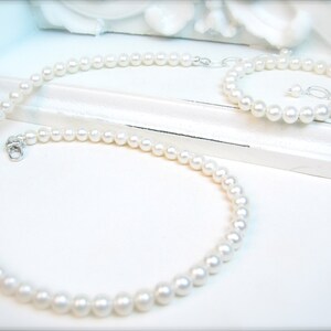 May include: A set of white pearl jewellery, comprising a necklace and a bracelet. Both the necklace and bracelet are made of small, round pearls.