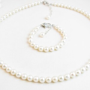 May include: A set of white pearl jewellery, comprising a necklace and a bracelet. Both pieces are made of white pearls and have a silver clasp.