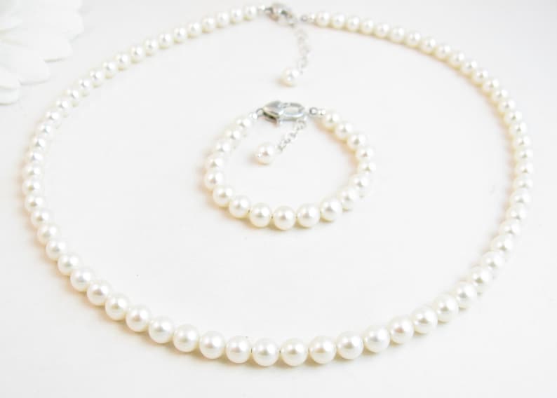 May include: A set of white pearl jewellery, comprising a necklace and a bracelet. Both pieces are made of white pearls and have a silver clasp.