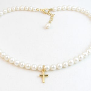 May include: A white pearl necklace with a gold cross pendant.