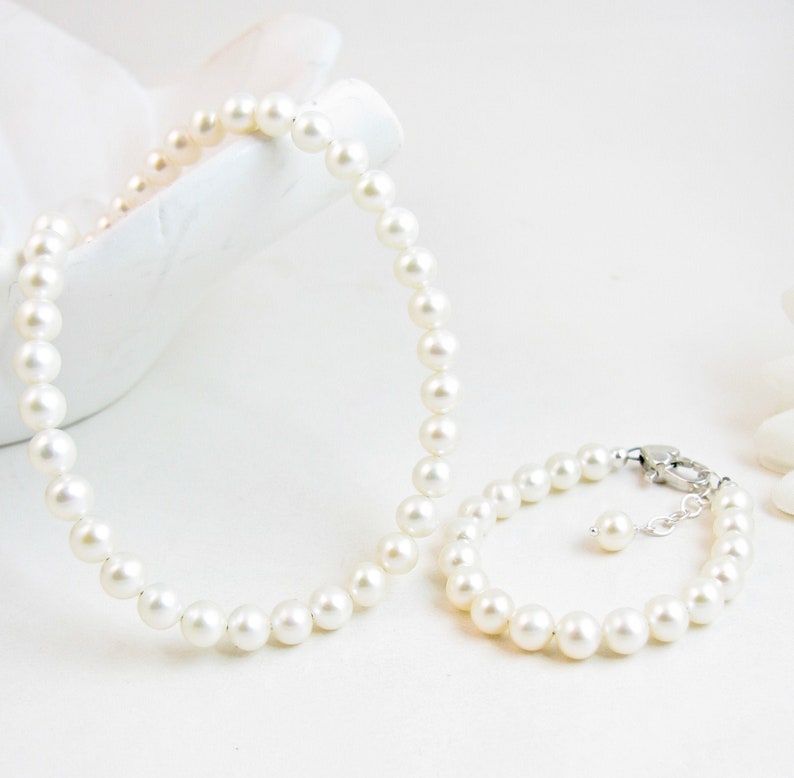 real pearl necklace and bracelet matching set. created with 5.5mm round white freshwater pearls and sterling silver heart shaped lobster clasps.