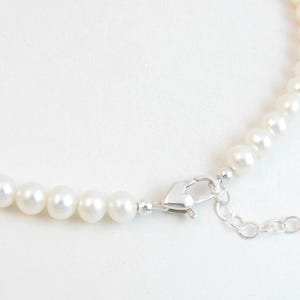 May include: A white pearl necklace with a silver clasp and extender chain.