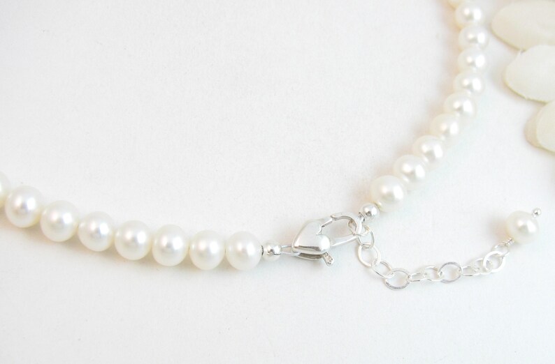 May include: A white pearl necklace with a silver clasp and extender chain.