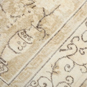 May include: Close-up of a beige and brown patterned rug. The rug features a detailed design with floral and geometric elements. The colour palette includes shades of beige, cream, and brown, creating a warm and inviting aesthetic.