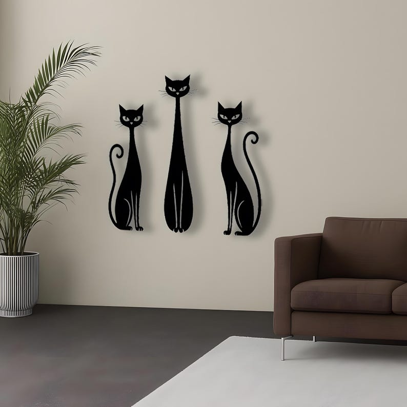 May include: A set of three black wall-mounted cat silhouettes. The two outer cats are depicted in a seated position with curled tails, while the central cat is taller and standing upright. Each cat features pointed ears and almond-shaped eyes.