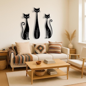 May include: A set of three black cat wall art pieces featuring stylized silhouettes. The two outer cats are depicted in a seated position with curled tails, while the central cat is taller and stands upright with a slender body and pointed ears.