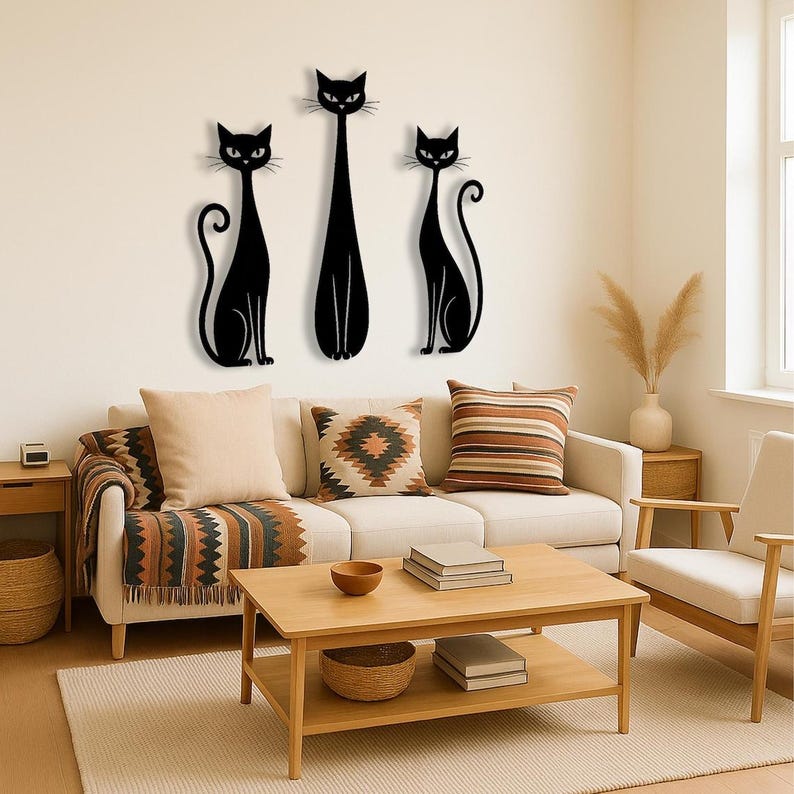 May include: A set of three black cat wall art pieces featuring stylized silhouettes. The two outer cats are depicted in a seated position with curled tails, while the central cat is taller and stands upright with a slender body and pointed ears.