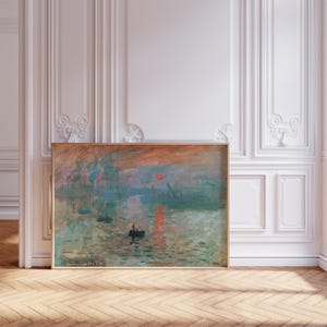 Puede incluir: Una pintura enmarcada que representa un paisaje marítimo con un sol rojo poniéndose sobre el agua. La pintura está en una paleta de colores apagados de azules, verdes y naranjas. Hay varios barcos en la distancia y un pequeño bote en primer plano.