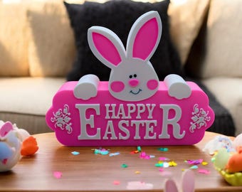 May include: Pink wooden sign with a white bunny peeking over the top. The sign says "Happy Easter" in white letters.