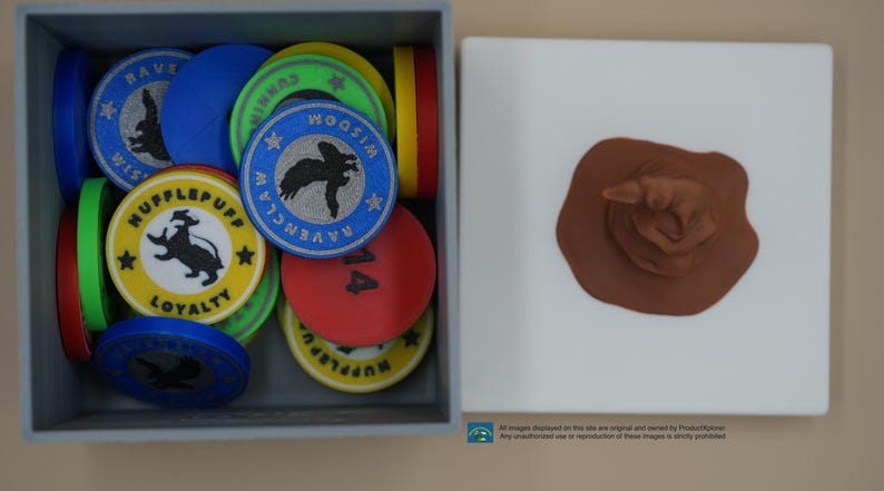 Pu&ograve; includere: Una scatola di gettoni rotondi colorati con vari stemmi e nomi di case dell'universo di Harry Potter, tra cui Ravenclaw, Tassorosso e Woosim. I gettoni sono in una scatola grigia con un cappello di smistamento marrone su una superficie bianca.