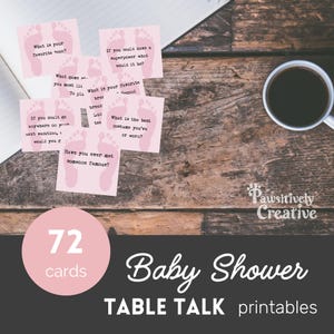 May include: A collection of pink baby shower table talk cards with questions such as "What is your favourite book?" and "If you could have a superpower what would it be?" A cup of coffee sits on a wooden table. The cards are labelled "72 cards" and "Baby Shower Table Talk printables."