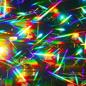May include: A holographic surface displaying a vibrant spectrum of light with intersecting diagonal beams in red, orange, yellow, green, blue, and violet. The light refraction creates a multi-colored pattern across the dark, reflective background.