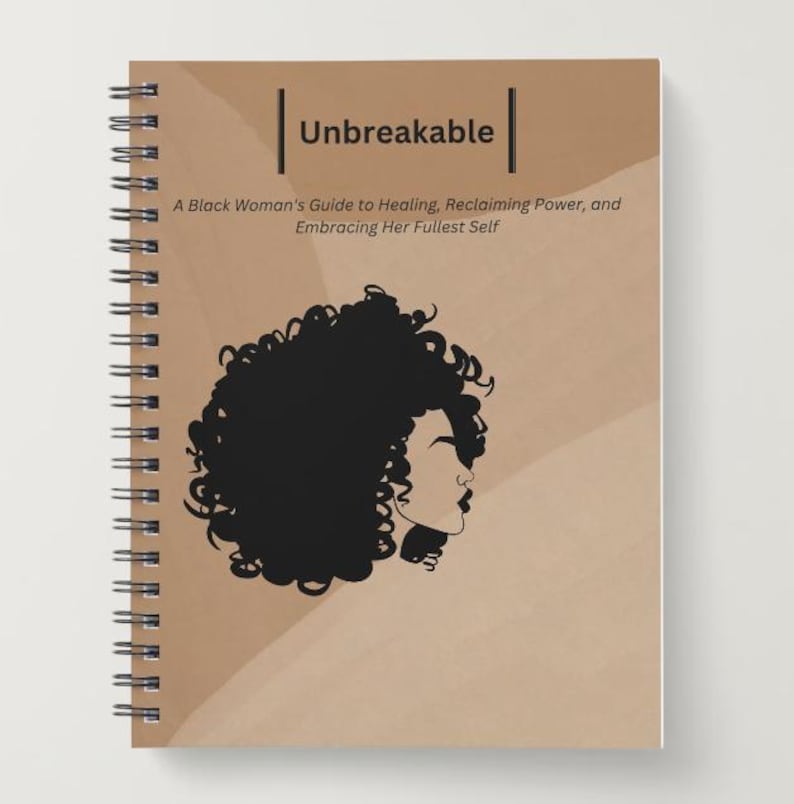 May include: A spiral bound journal with a brown cover featuring a black silhouette of a woman with curly hair. The title "Unbreakable" is printed in white on the cover, along with the text "A Black Woman's Guide to Healing, Reclaiming Power, and Embracing Her Fullest Self."