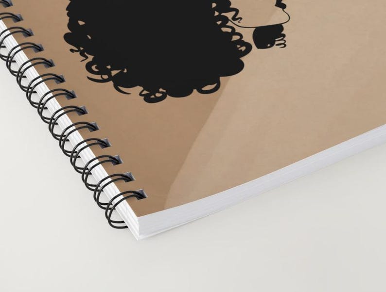 May include: A brown spiral notebook with a black silhouette of a person with curly hair. The notebook is closed and the spine is visible.