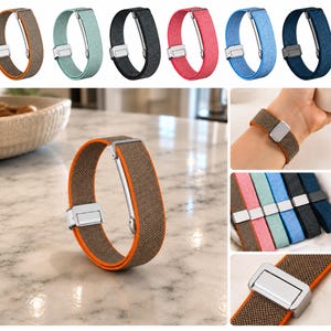 May include: A collection of elastic watch bands featuring a textured fabric exterior and a contrasting colored interior lining. Each band includes a metallic silver-toned magnetic clasp mechanism. The bands are available in brown, mint green, black, pink, light blue, and dark blue.