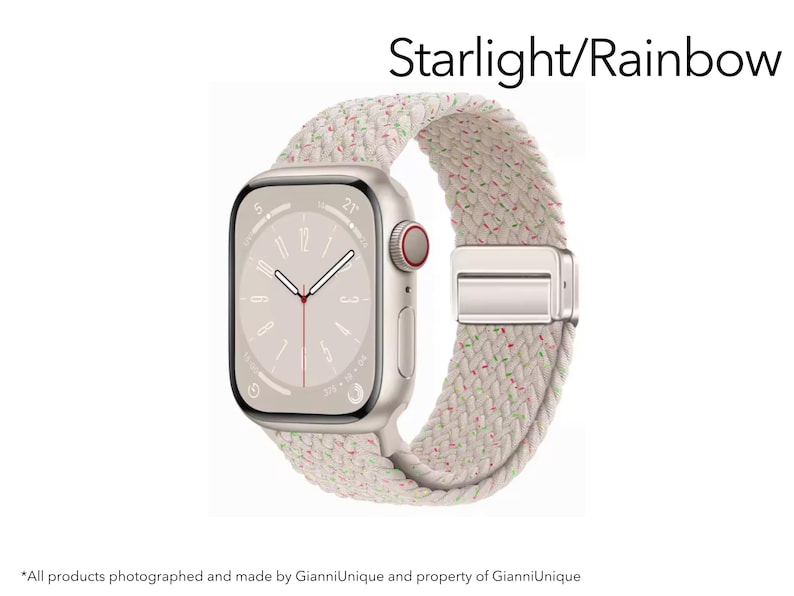 May include: A smartwatch with a rectangular starlight-colored case and a braided band featuring a starlight base with small, scattered rainbow-colored flecks. The watch face displays a minimalist analog clock design with the text Starlight/Rainbow.